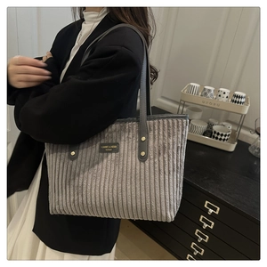 Dettaglio della borsa tote in velluto a coste grigio con etichetta logo nera
