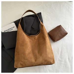 Sac hobo en daim marron avec pochette assortie sur fond de tissu blanc épuré