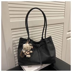 Detail of a large black vintage tote bag with pleated texture and a plush cat charm