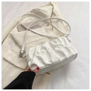 Close-up of white pleated cloud bag on beige blazer with fine leather texture detail