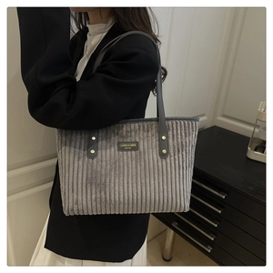 Détail du sac cabas en velours côtelé gris avec étiquette en cuir et bandoulière