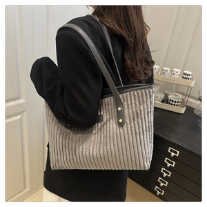 Détail du sac cabas en velours gris avec bandoulière en cuir et rivets dorés sur modèle
