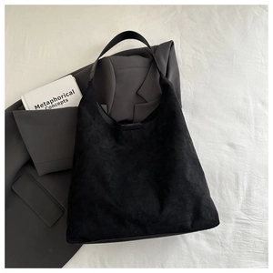 Gros plan du sac hobo en daim noir minimaliste avec finition mate sur tissu blanc
