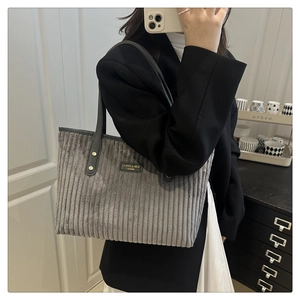 Dettaglio della borsa tote in velluto grigio con trama spessa e manici in pelle con rivetti