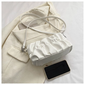 Detailed close-up of white pleated cloud bag on beige blazer with silver hardware
