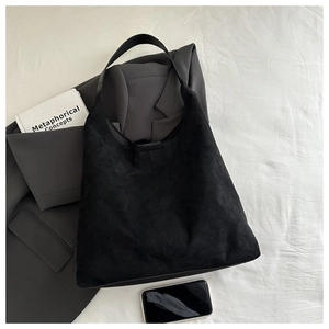 Vue détaillée du grand sac cabas noir en daim sur fond de tissu blanc texturé