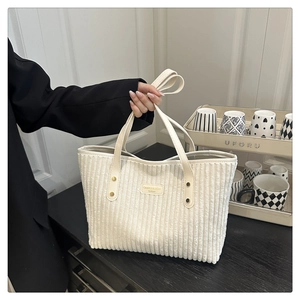 Detail van de witte corduroy draagtas met leren embleem en metalen klinknagels