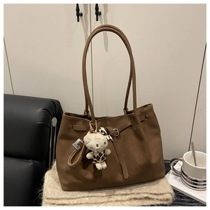 Close-up of brown vintage tote bag with pleated texture and stylish kitten plush pendant