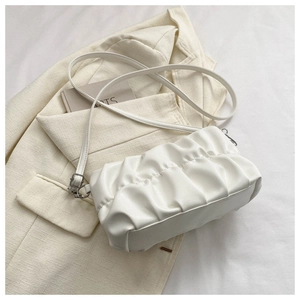 Detail showing white pleated cloud bag with soft leather texture and adjustable strap