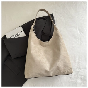 Détail d'un cabas minimaliste en daim beige avec un blazer et un livre dans un décor lifestyle