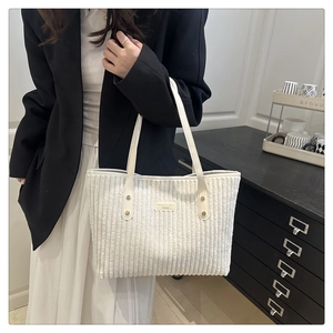 Dettaglio della borsa tote in velluto a coste bianco con manici in pelle e logo