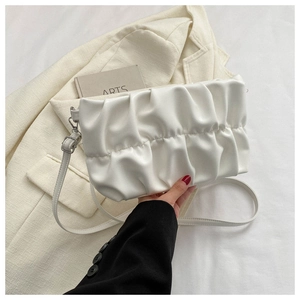 Close-up of white ruched leather handbag held by model over a cream blazer