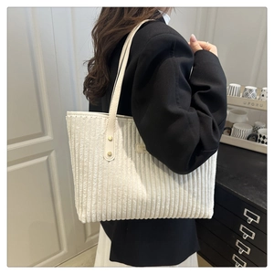 Dettaglio della borsa tote in velluto a coste bianco crema con manici in pelle