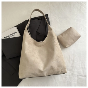Détails du sac fourre-tout beige en daim avec sa pochette zippée assortie posée sur tissu