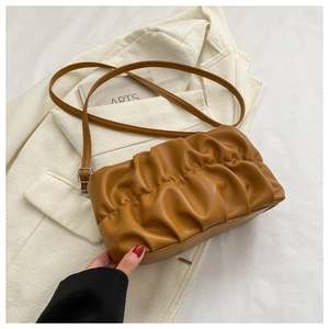 Detail of caramel pleated shoulder bag with matte leather texture and long strap