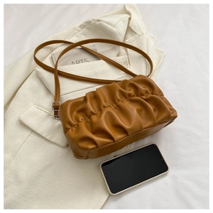 Detail of caramel pleated cloud bag featuring soft leather texture and adjustable strap