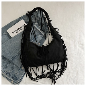 Detail of bohemian black suede tote bag featuring long fringes and soft tie closure