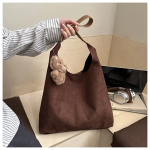 Dettaglio della borsa hobo in pelle scamosciata marrone scuro con ciondolo a orsetto