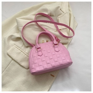 Detalle de bolso rosa con textura de cocodrilo sobre una americana beige suave