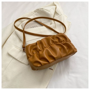 Detail of a brown pleated cloud bag with soft PU leather texture on a cream blazer