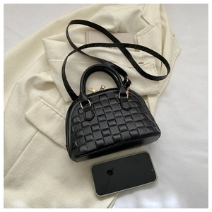 Detalle del bolso de concha negro a cuadros con cremallera dorada y smartphone para escala