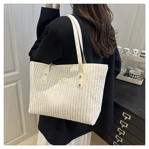 Dettaglio della borsa tote in velluto a coste con patch logo e rivetti in metallo