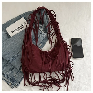 Close-up of bohemian burgundy suede tote with long fringes on casual lifestyle background