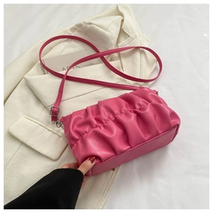 Detail of rose pink pleated handbag on white blazer with adjustable shoulder strap