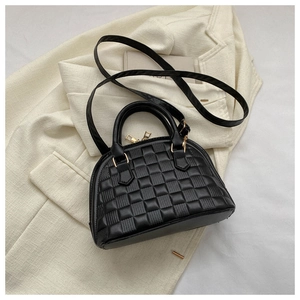 Primer plano del bolso de concha negro con textura tejida y cremallera de metal dorado