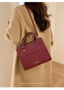 Dettaglio di una borsa tote bordeaux con trama martellata e scritta del logo bianca