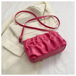 Close-up of pink pleated cloud bag with metallic buckle on white fabric background