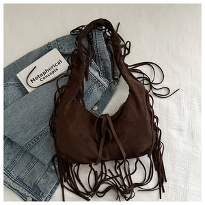 Close-up of vintage brown suede tote bag featuring long bohemian tassels on fabric