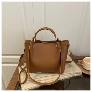 Detail of brown litchi pattern leather tote with gold U-shaped handle and shoulder strap