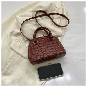 Detalle de bolso concha marrón de cocodrilo con herrajes dorados sobre blazer