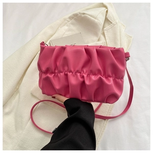 Close-up of vibrant pink ruched dumpling bag with smooth leather texture and matching strap