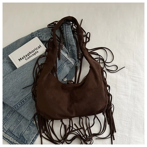 Detail of dark brown suede shoulder bag featuring long bohemian tassels and half-moon shape