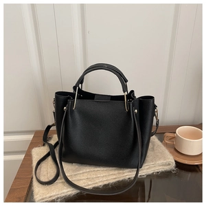 Close-up of black litchi pattern leather handbag with metal ring handle and strap