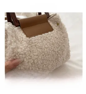Detail of soft cream faux shearling texture with brown leather accents on a tote bag