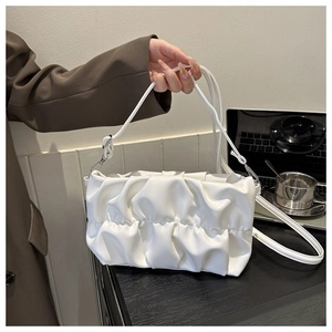 Close-up of white ruched shoulder bag held by model in a minimalist urban office setting
