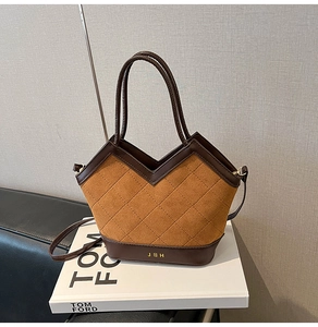 Detail of vintage tote bag with quilted stitching, brown leather, and metal letter logo