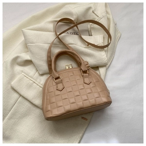 Detalle del bolso de concha caqui claro con textura acolchada y cremalleras doradas