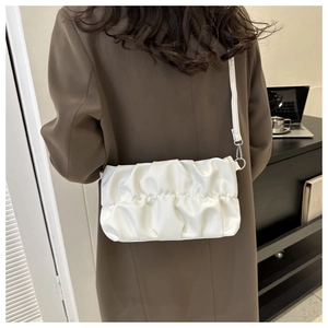 Close-up of white pleated cloud bag with shiny leather texture and silver buckle
