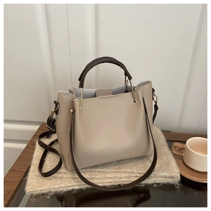 Close-up of beige litchi grain tote bag on knit fabric with coffee cup and golden hardware