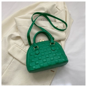 Vista superior de un bolso de concha verde acolchado con herrajes dorados sobre blazer