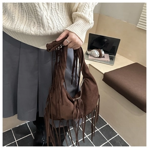 Detailed view of a brown suede crescent bag with long fringes and metal zipper