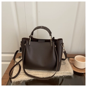 Detailed close-up of dark brown lychee texture leather tote bag with metallic hardware