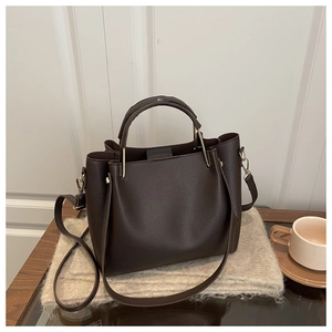 Detail of dark brown pebble leather tote bag with round handles and long strap