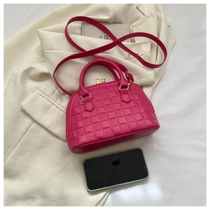 Detalle de mini bolso rosa con relieve de cuadros sobre fondo de chaqueta beige