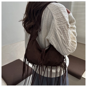 Deep brown suede tassel shoulder bag styled with a white knit sweater in a cozy room