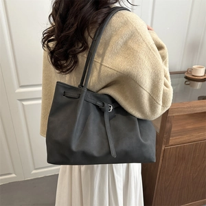 Minimalist black leather tote bag with pleated detail and long shoulder straps for women